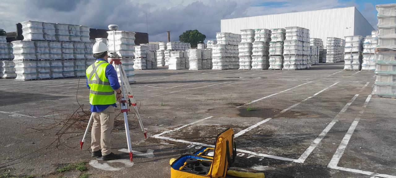 Topógrafo da Ageomap operando equipamento em pátio industrial com fardos empilhados